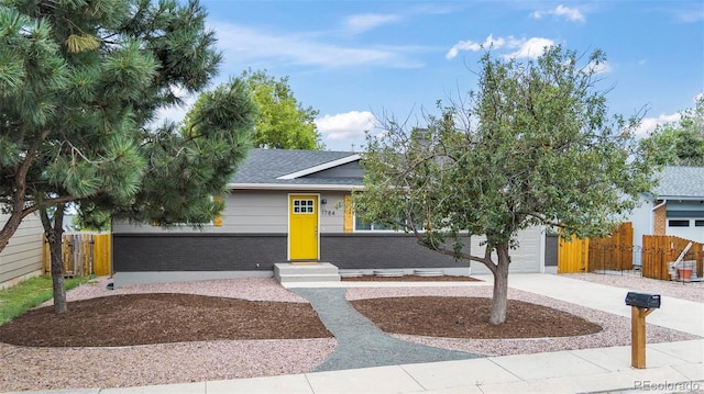 obstructed view of property featuring a garage, brick siding, driveway, and fence