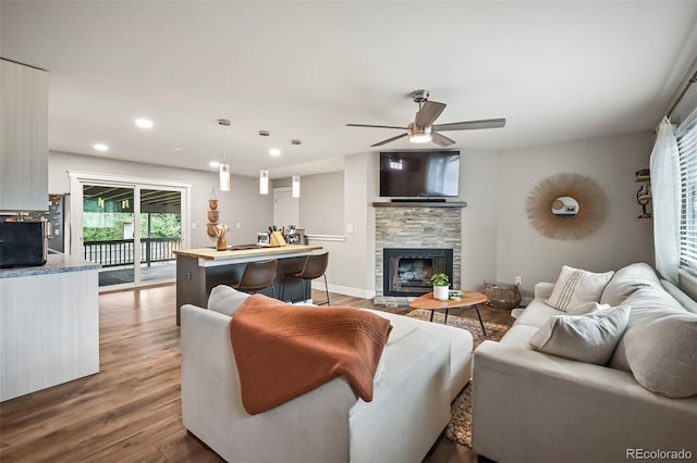 living room with a fireplace, recessed lighting, a ceiling fan, wood finished floors, and baseboards