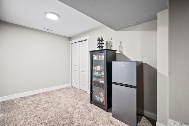 interior space with carpet flooring, freestanding refrigerator, and baseboards