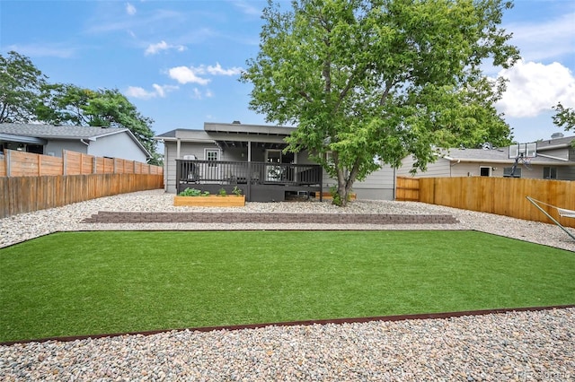 rear view of property featuring a deck, a lawn, and a fenced backyard