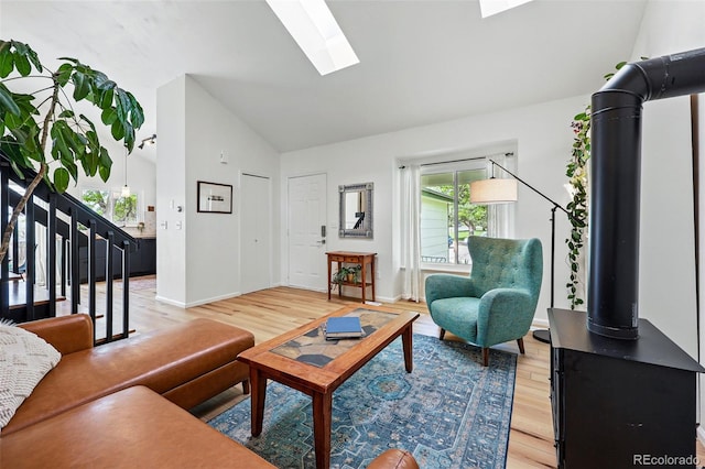 living area with light wood-type flooring, healthy amount of natural light, a skylight, high vaulted ceiling, and baseboards