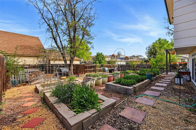 fenced backyard with a vegetable garden and a residential view
