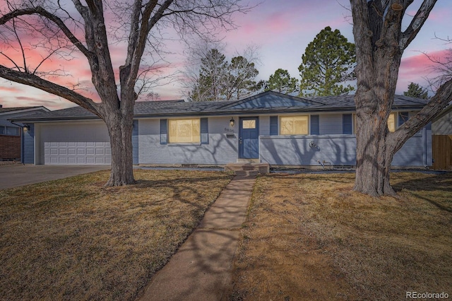 ranch-style home featuring an attached garage, concrete driveway, and a front yard