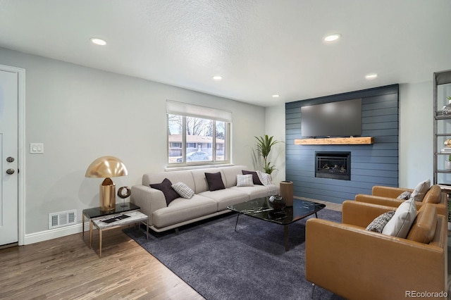 living room with visible vents, recessed lighting, a large fireplace, and wood finished floors