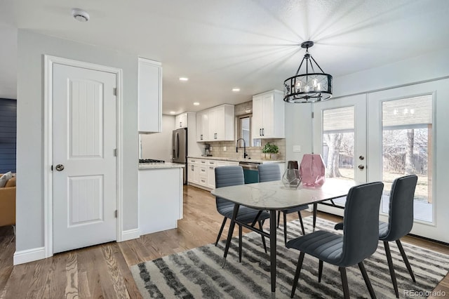 dining area featuring light wood finished floors, recessed lighting, an inviting chandelier, and baseboards