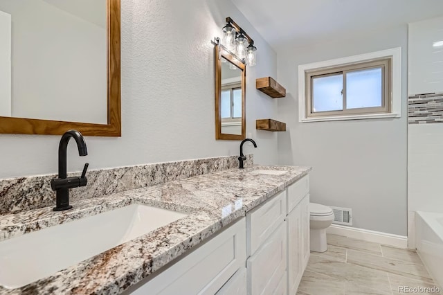 bathroom featuring a bathtub, visible vents, toilet, and a sink