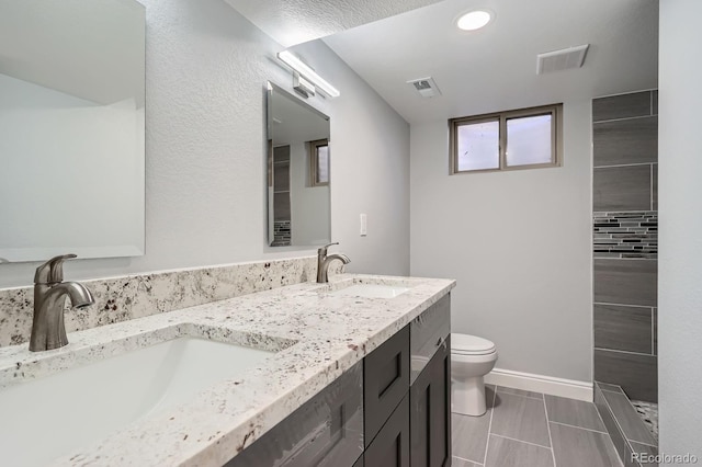 full bath with toilet, baseboards, visible vents, and a sink