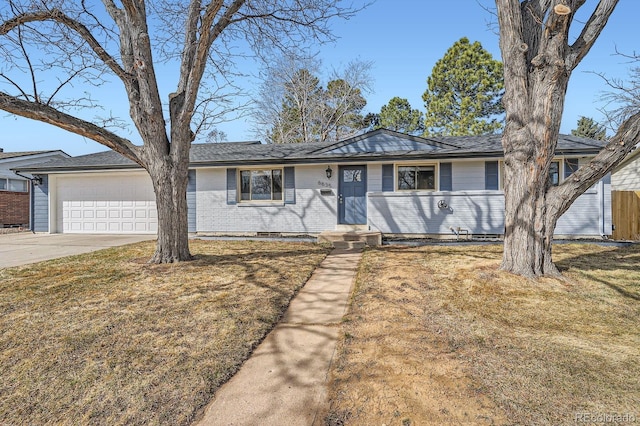 single story home featuring brick siding, concrete driveway, a garage, and a front yard