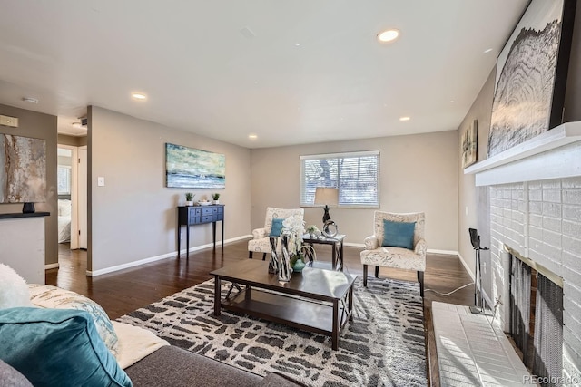 living room with recessed lighting, a brick fireplace, baseboards, and wood finished floors