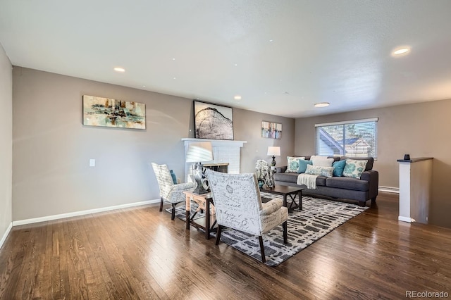 living area with recessed lighting, a baseboard heating unit, wood finished floors, baseboards, and a brick fireplace