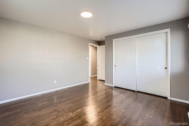 unfurnished bedroom with a closet, wood finished floors, and baseboards