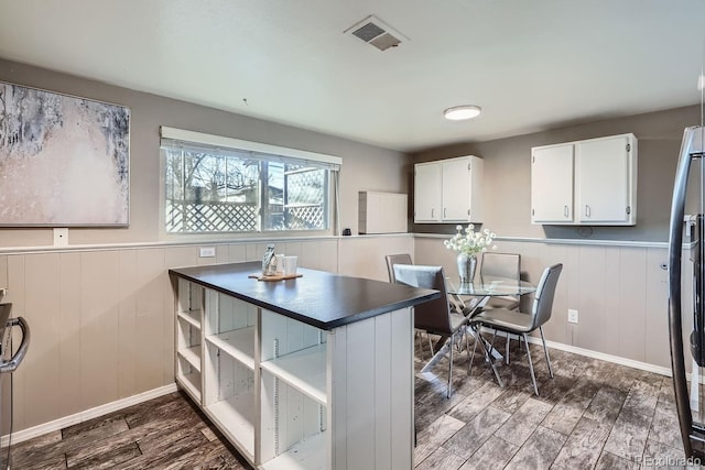 kitchen featuring a wainscoted wall, dark wood-style flooring, visible vents, white cabinets, and dark countertops