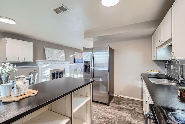 kitchen featuring stainless steel fridge, visible vents, dark countertops, a sink, and range with electric stovetop