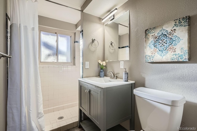 full bath featuring a textured wall, a stall shower, vanity, and toilet