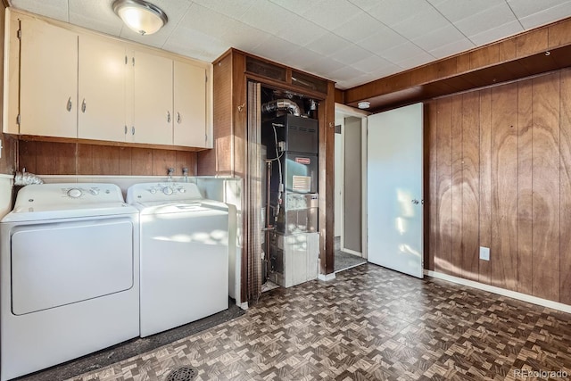 clothes washing area featuring separate washer and dryer, wood walls, and cabinet space