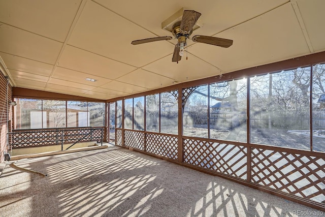 unfurnished sunroom featuring plenty of natural light, a ceiling fan, and a drop ceiling