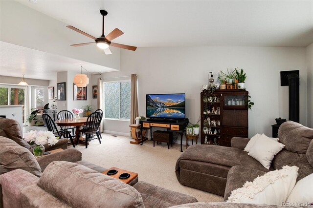 8129 Locust Dr, Littleton, CO 80125 - living area featuring light colored carpet, ceiling fan, plenty of natural light, lofted ceiling, and a wood stove