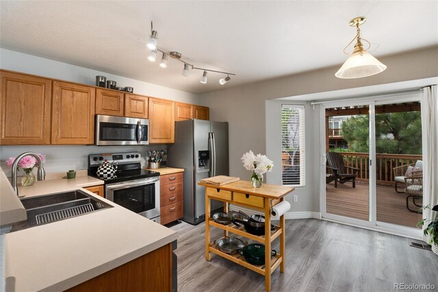 8129 Locust Dr, Littleton, CO 80125 - kitchen with stainless steel appliances, a sink, light countertops, light wood-style floors, and decorative light fixtures