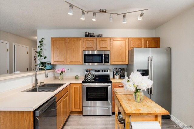 8129 Locust Dr, Littleton, CO 80125 - kitchen featuring stainless steel appliances, a sink, light wood-style flooring, a peninsula, and wooden counters