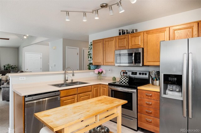 8129 Locust Dr, Littleton, CO 80125 - kitchen with appliances with stainless steel finishes, a sink, a peninsula, open floor plan, and light countertops