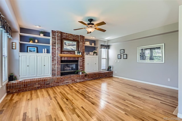 5305 W Lake Pl, Littleton, CO 80123 - unfurnished living room with built in features, a ceiling fan, light wood-style flooring, a brick fireplace, and baseboards