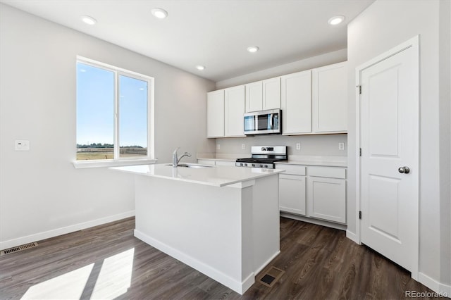 kitchen featuring white cabinetry, a center island with sink, appliances with stainless steel finishes, and dark hardwood / wood-style floors