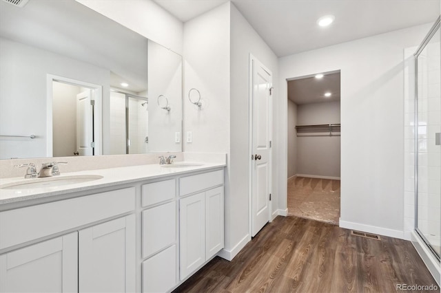 bathroom featuring hardwood / wood-style flooring, vanity, and an enclosed shower