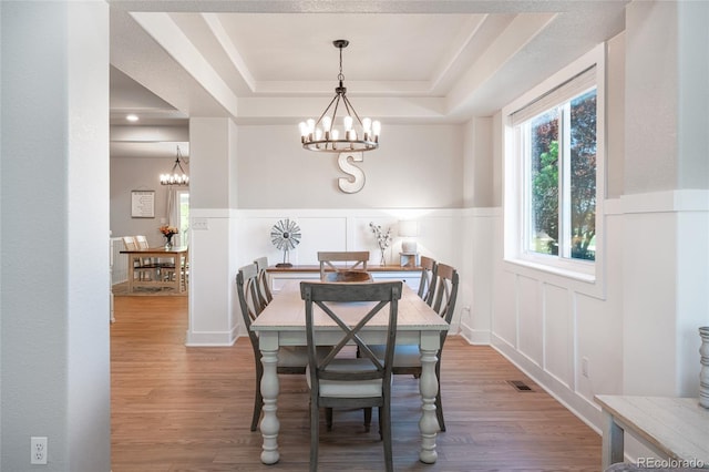 6488 Tilbury Ave, Firestone, CO 80504 - dining space with a chandelier, a raised ceiling, wood finished floors, wainscoting, and a decorative wall