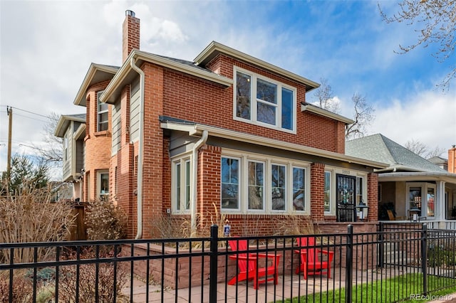 view of side of home featuring brick siding, a chimney, and a fenced front yard