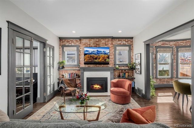 living room featuring visible vents, wood finished floors, recessed lighting, a large fireplace, and brick wall