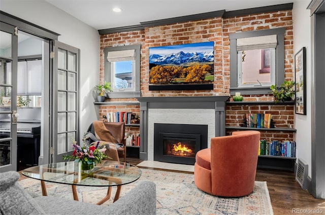 living area with visible vents, brick wall, wood finished floors, and a fireplace