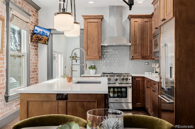 kitchen featuring a sink, decorative backsplash, light countertops, built in appliances, and wall chimney exhaust hood