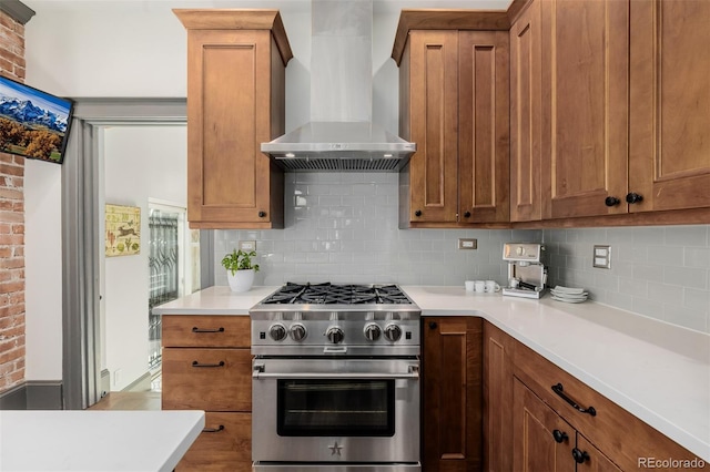 kitchen with stainless steel stove, brown cabinets, and wall chimney range hood