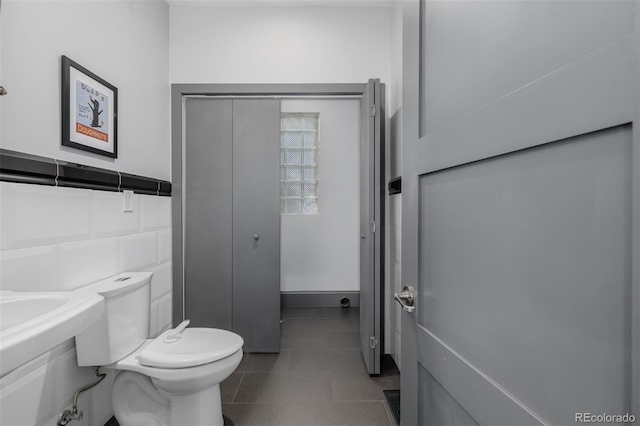 bathroom with tile patterned floors, toilet, tile walls, and wainscoting