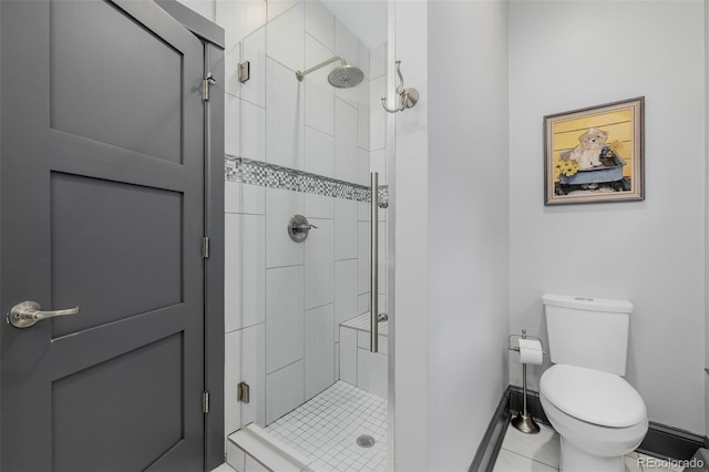 bathroom featuring a stall shower, toilet, and baseboards