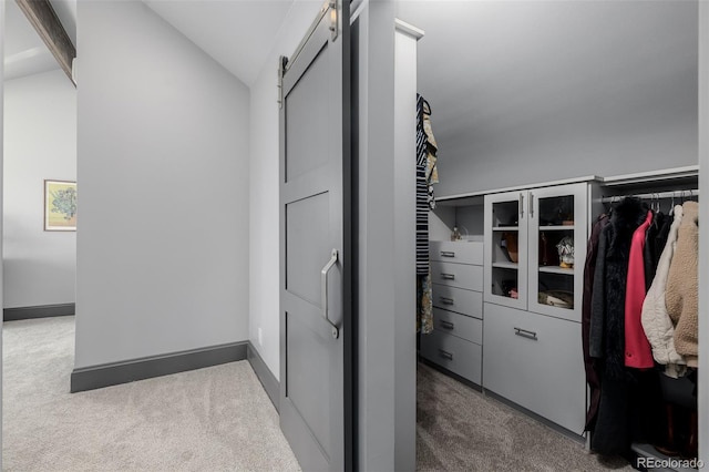 walk in closet featuring vaulted ceiling, a barn door, and carpet floors