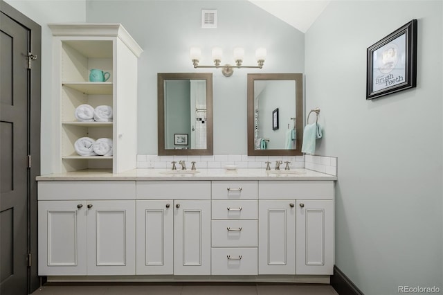 bathroom with double vanity, built in shelves, visible vents, and a sink