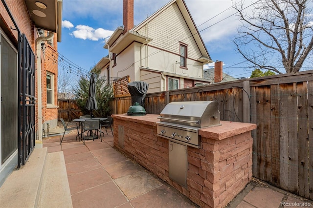 view of patio / terrace with outdoor dining space, an outdoor kitchen, a grill, and a fenced backyard