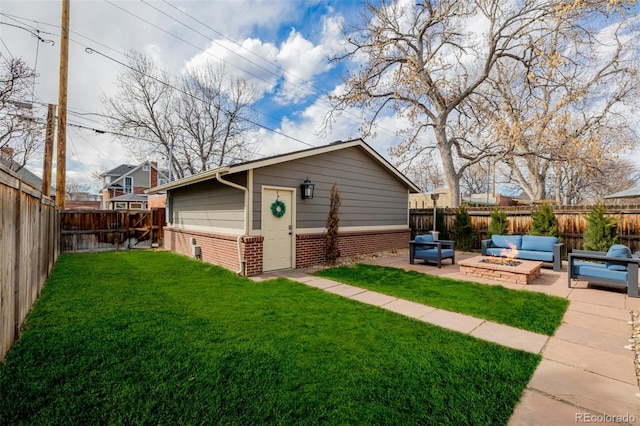 exterior space with a yard, a fenced backyard, an outdoor living space with a fire pit, a patio area, and brick siding