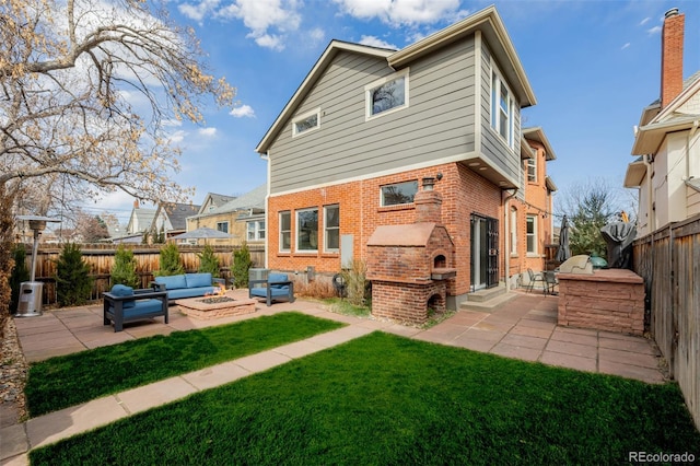 back of property featuring exterior kitchen, a fenced backyard, an outdoor living space with a fire pit, a patio area, and brick siding