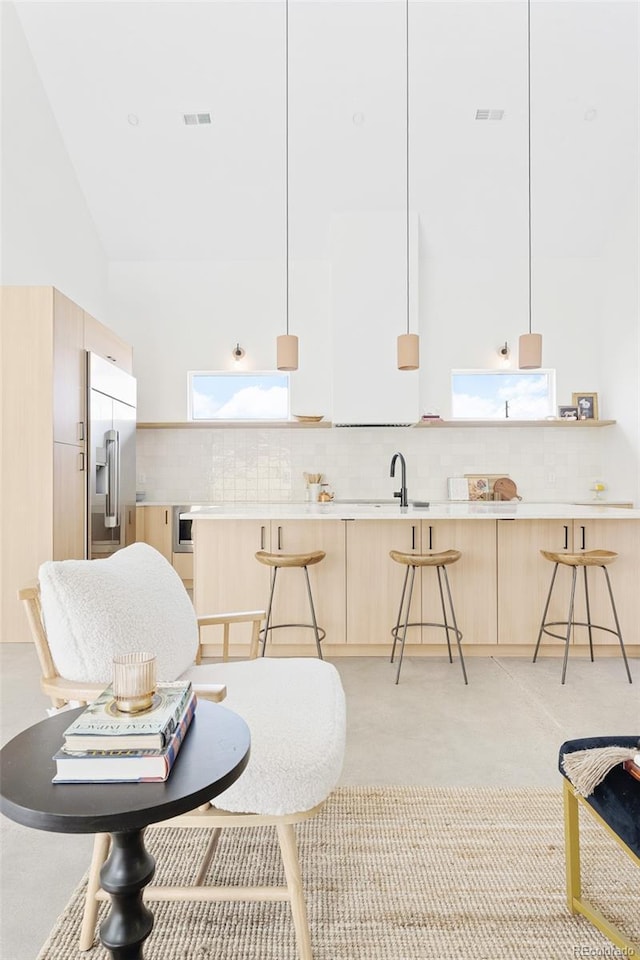 interior space featuring modern cabinets, light brown cabinetry, a breakfast bar area, and built in refrigerator