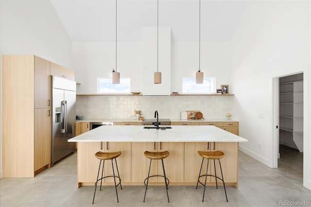 kitchen with light countertops, light brown cabinetry, stainless steel built in refrigerator, and decorative backsplash