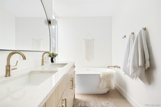 full bathroom featuring baseboards, a freestanding tub, a sink, and double vanity