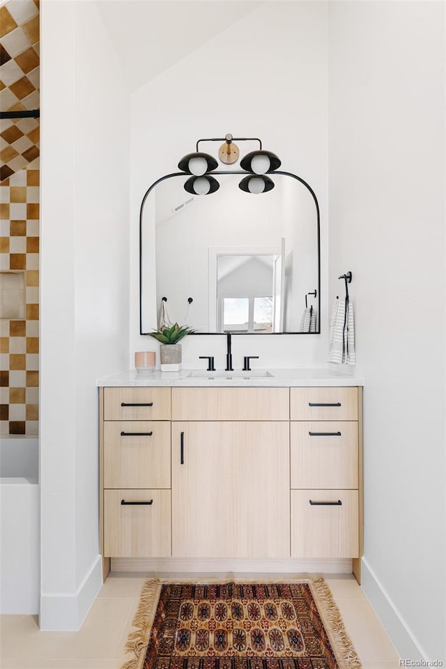 full bath with vaulted ceiling, baseboards, tile patterned flooring, and vanity