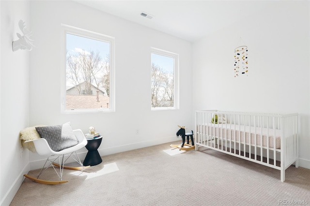 unfurnished bedroom with visible vents, baseboards, carpet flooring, and a nursery area
