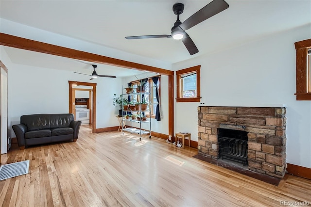 living area featuring baseboards, wood finished floors, ceiling fan, and a fireplace