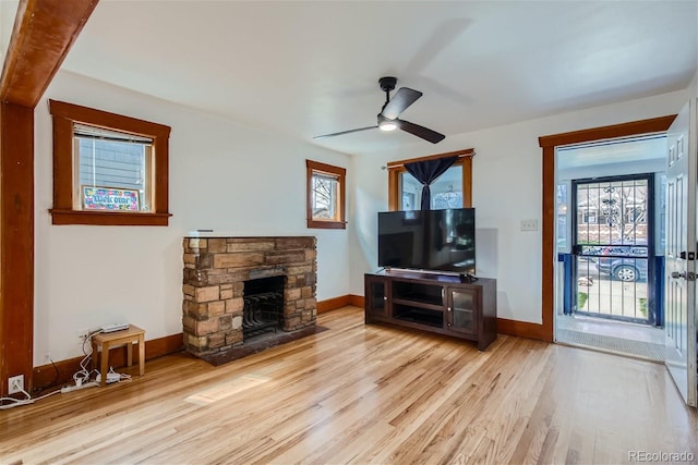 living room featuring a fireplace, wood finished floors, baseboards, and a ceiling fan