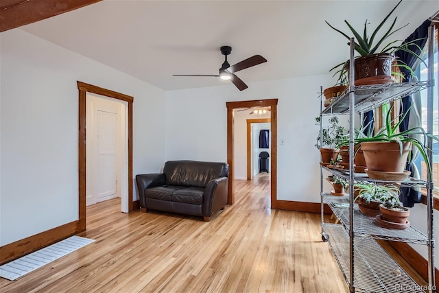 living area featuring ceiling fan, baseboards, and light wood-style floors