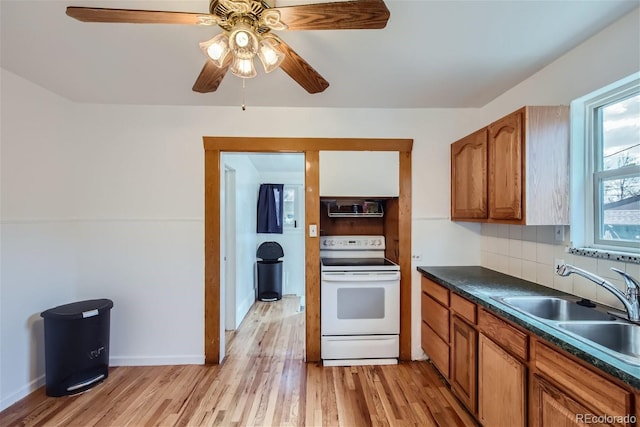 kitchen featuring a ceiling fan, a sink, electric stove, dark countertops, and tasteful backsplash