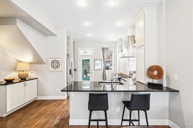 kitchen featuring kitchen peninsula, white cabinetry, and dark stone countertops